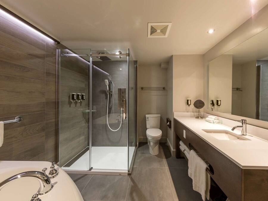 Un baño moderno con ducha envuelta en vidrio, un lavabo blanco y un espejo grande.
