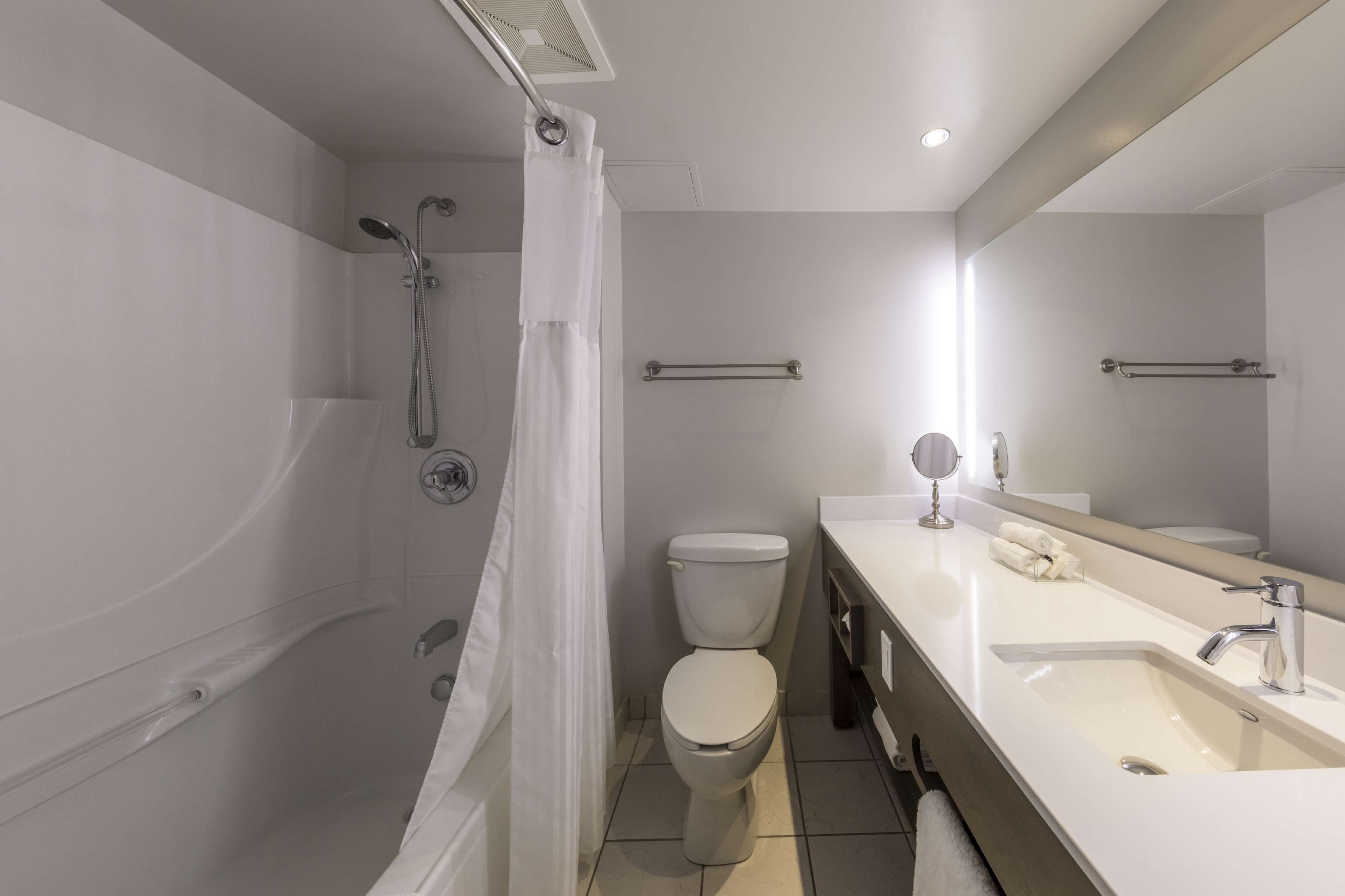 Un baño moderno con bañera, ducha, inodoro y tocador con espejo.