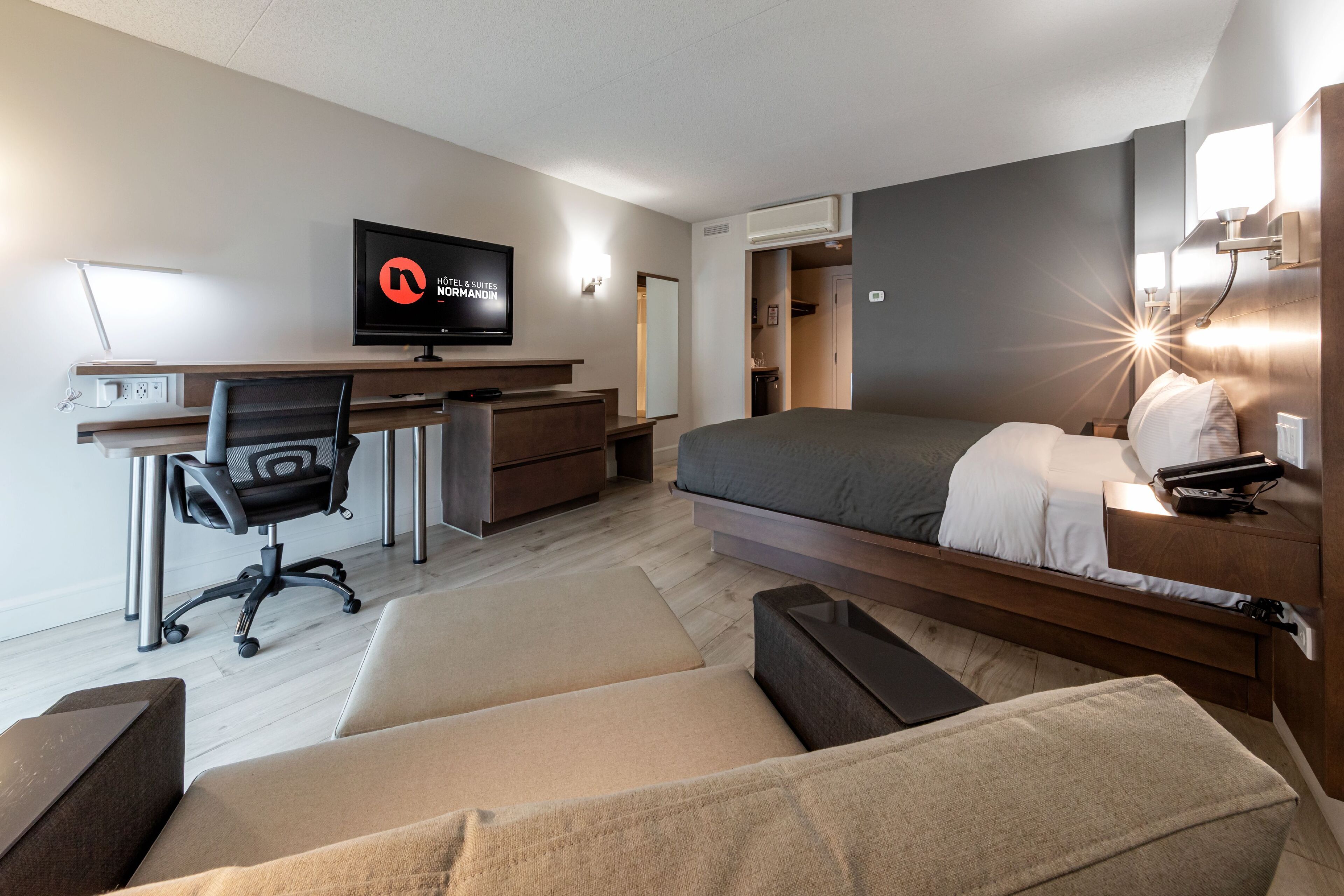 Habitació d'hotel moderna amb llit, escriptori, cadira i televisió.