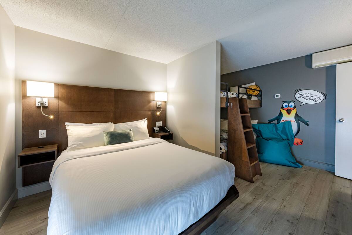 A hotel room with a large bed, bedside tables, a wardrobe, and a wall mural.