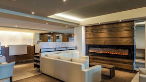 A modern living area with a fireplace, a sofa, and a reception desk. - Hôtel & Suites Normandin Quebec (Québec City)