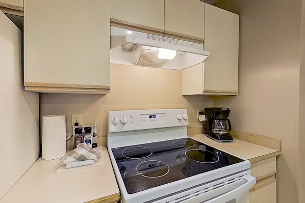 A compact kitchen with a white stove, a coffee maker, and a small countertop.