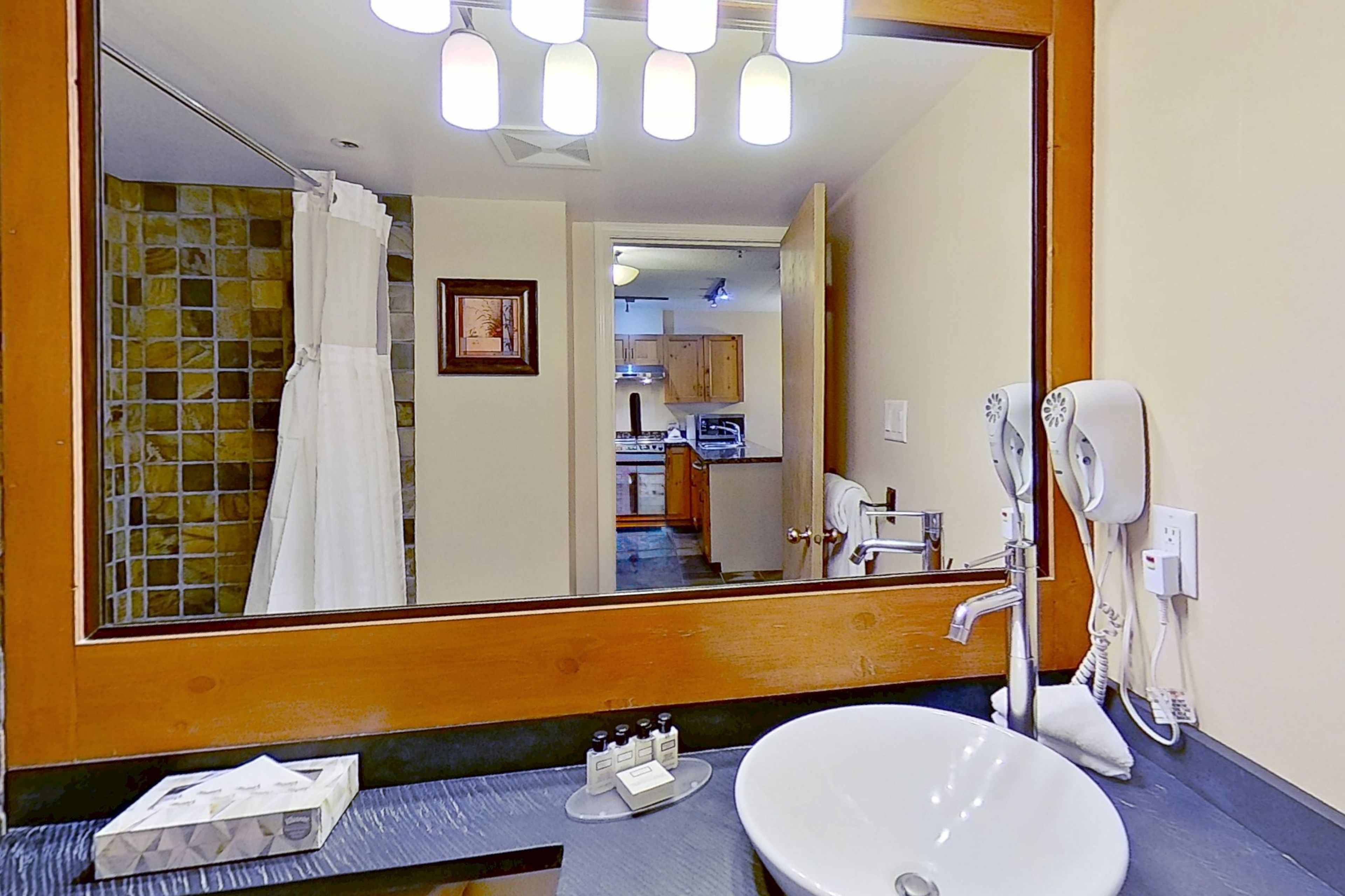 A bathroom with a large mirror, a sink, and a hairdryer.