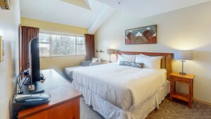 Habitación de hotel con una cama grande, un escritorio con computadora, una lámpara y un cuadro en la pared.