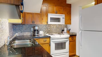 Una cocina con armarios de madera, estufa blanca, microondas y refrigerador.