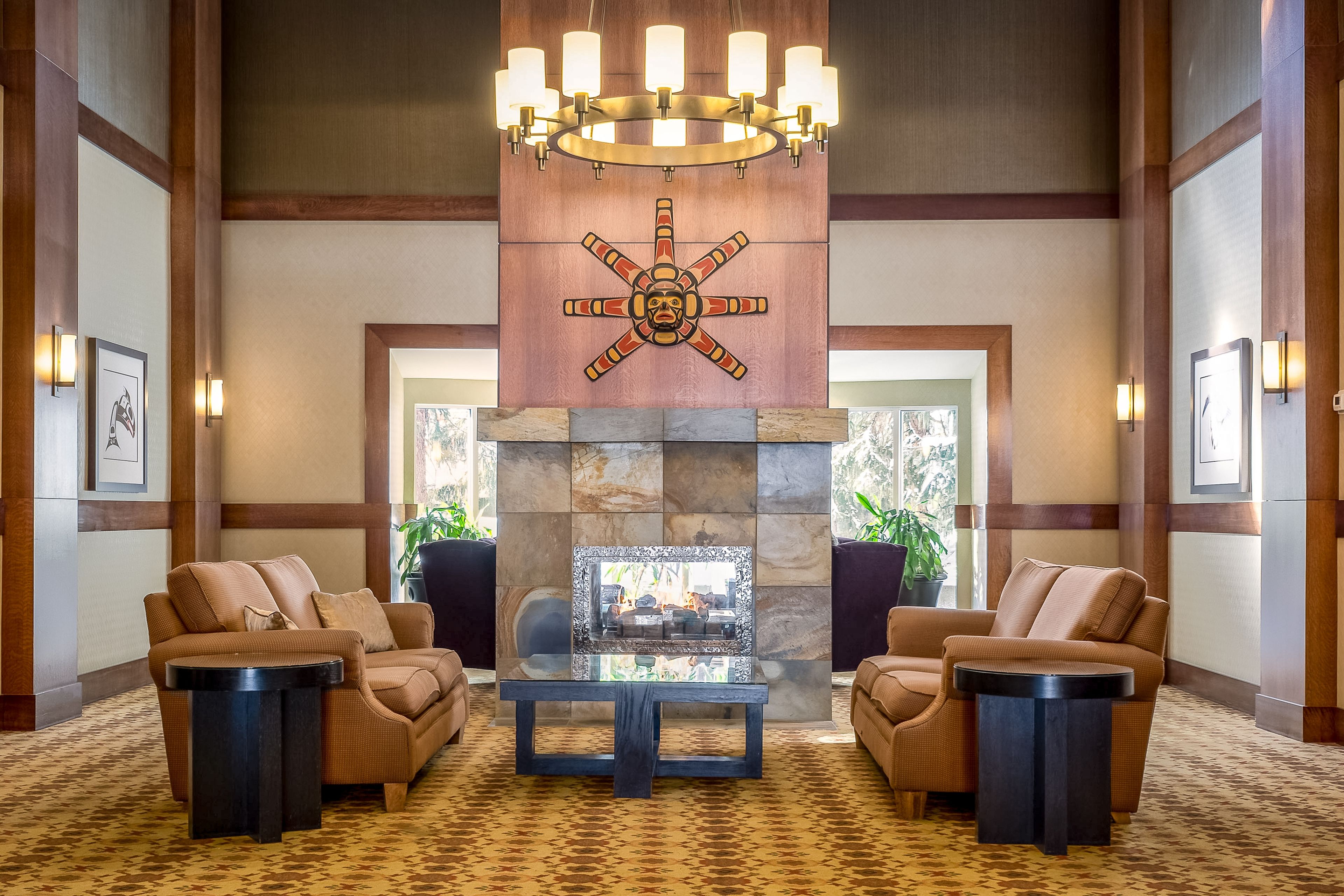 A lobby with a stone fireplace, leather sofas, a glass coffee table, and a chandelier.
