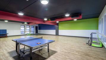 Enjoy a game of ping pong on our indoor sports facility's table, surrounded by a spacious floor and sports area.