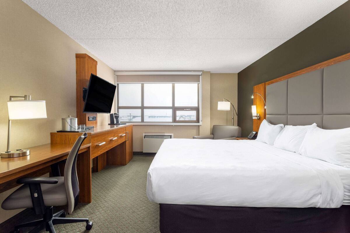 Habitación de hotel con cama, escritorio, silla, televisor y ventana con vistas.