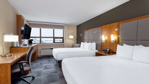 Une chambre d’hôtel avec deux lits, un bureau avec une chaise, une télévision et une fenêtre donnant sur un paysage agréable.