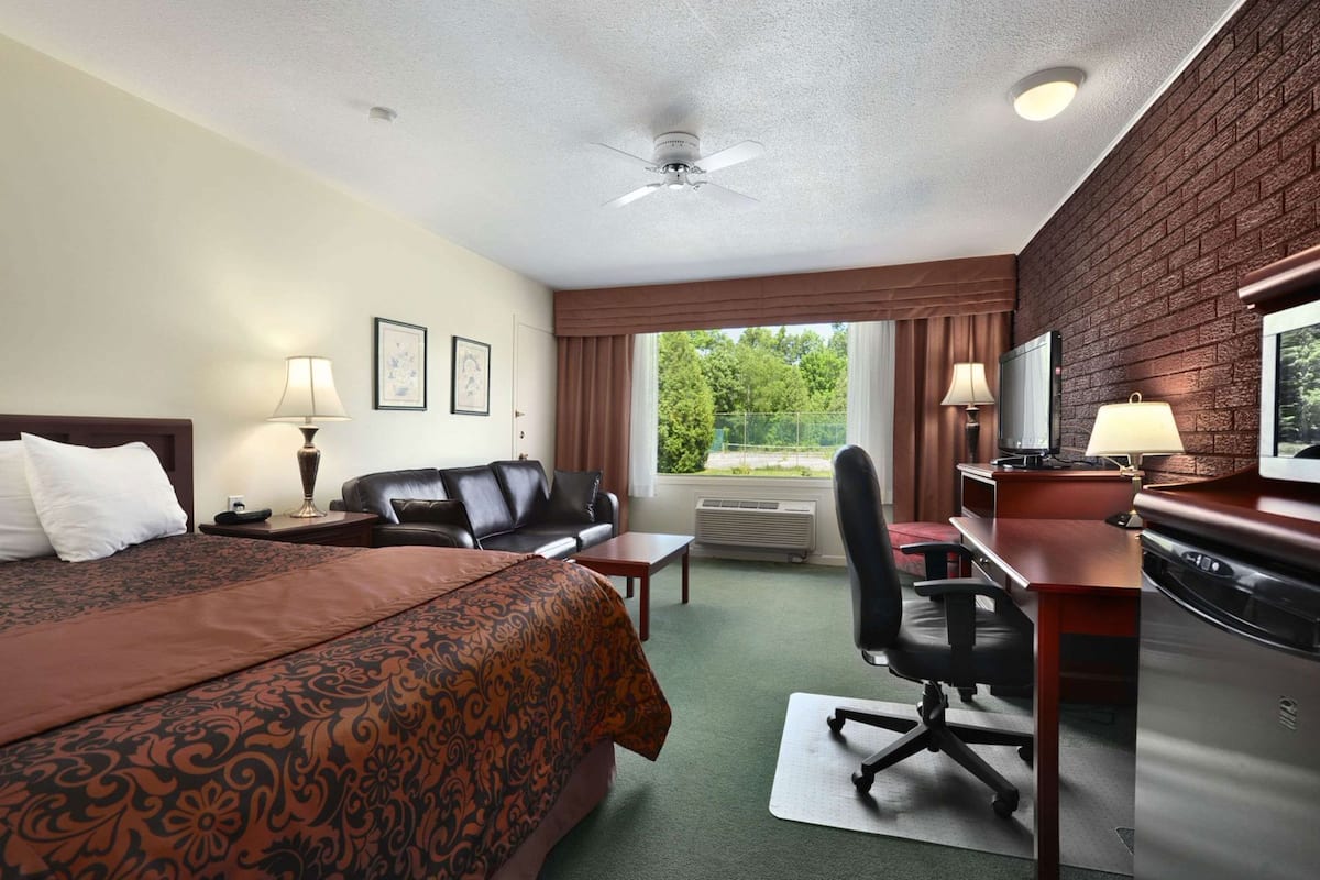 A hotel room with a bed, a desk, a chair, a television, and a window with curtains.