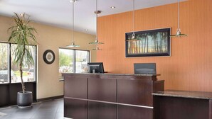 A reception desk with a computer, a clock, and a framed picture on the wall.