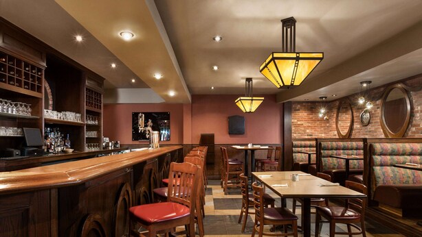 A restaurant with wooden bar and booths, tables, and chairs.