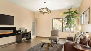 A modern living room with a fireplace, a glass coffee table, a leather sofa, and a large window with a view.