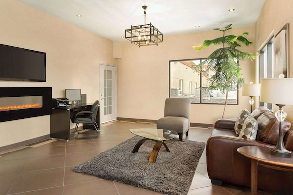 A modern living room with a fireplace, a glass coffee table, a leather sofa, and a large window with a view.