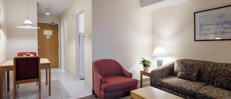 Uma sala de estar mobiliada com sofá, poltrona, mesa de centro e um espaço de jantar com mesa e cadeiras.