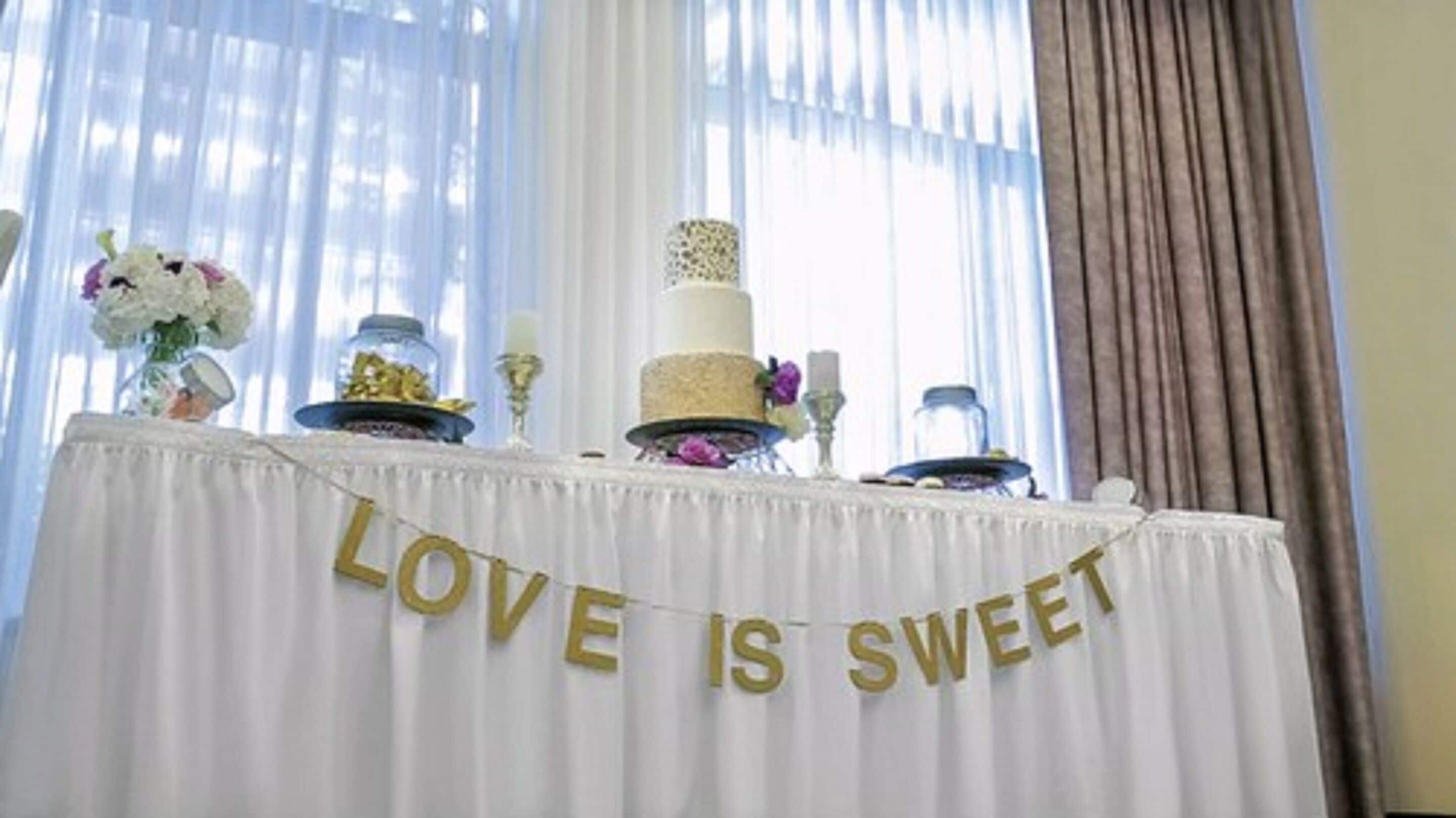 A table with a white tablecloth and a banner that reads "LOVE IS SWEET".