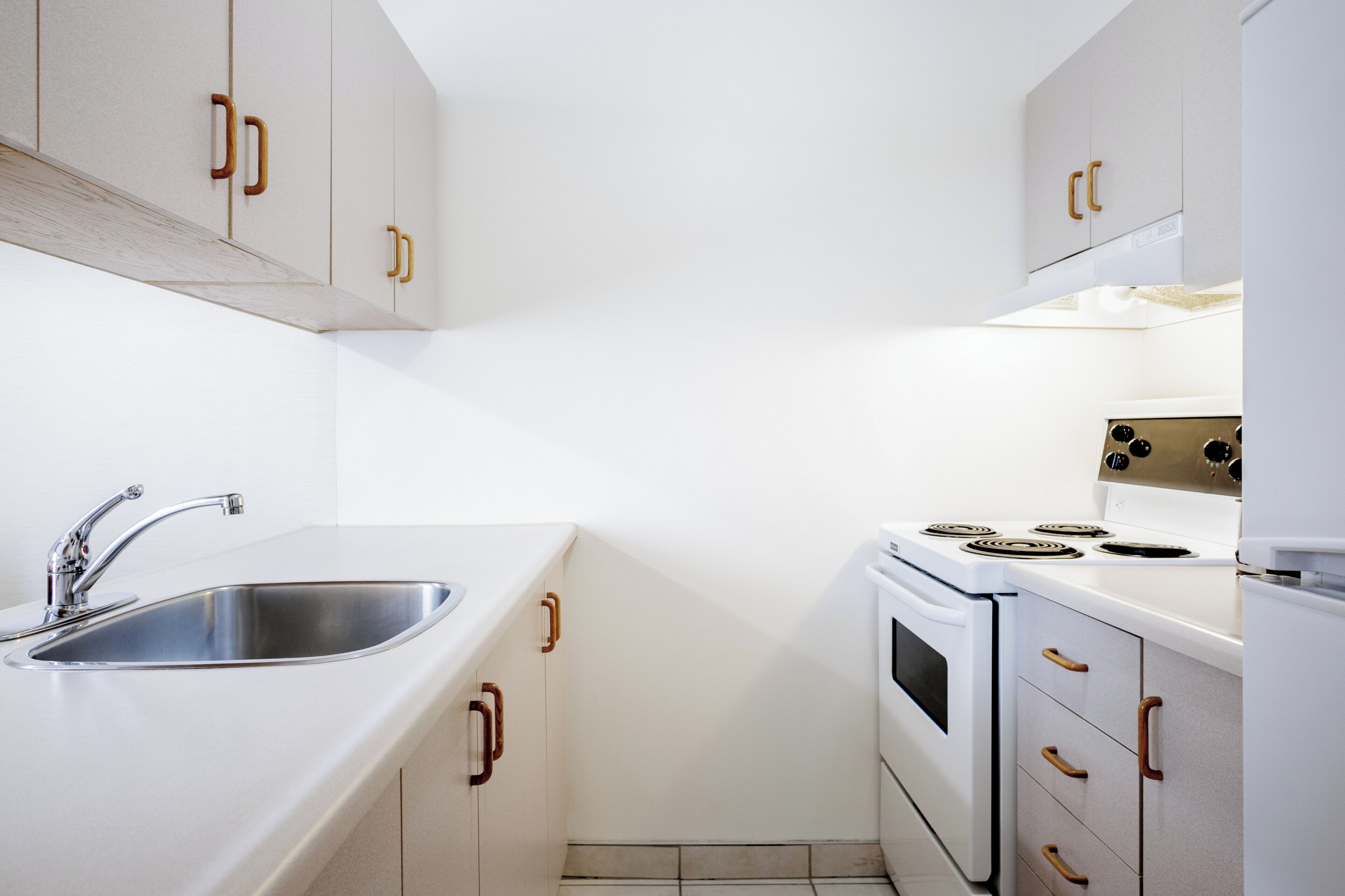 A kitchen with white cabinets, a stainless steel sink, and a stove.