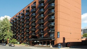 A multi-story hotel with a brick facade, numerous balconies, and a covered entrance area. - Cartier Place Suite Hotel (Ottawa)