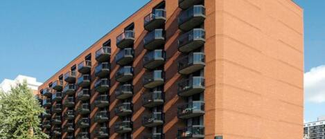 A multi-story hotel with a brick facade, numerous balconies, and a covered entrance area.