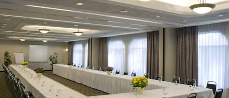 A conference room with a long table, chairs, and a projector screen.