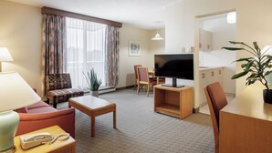 A hotel room with a sofa, a television, a table, a lamp, a telephone, and a potted plant. - Cartier Place Suite Hotel (Ottawa)