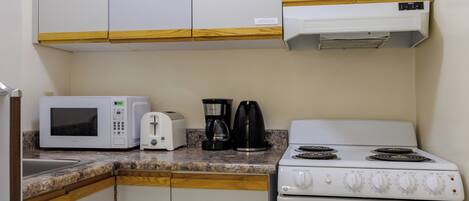Eine Küche mit Mikrowelle, Toaster, Kaffeemaschine und Herd.