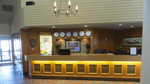 A reception desk with a clock, a chandelier, and a patterned carpet. - Paradise Inn & Conference Centre (Grande Prairie)
