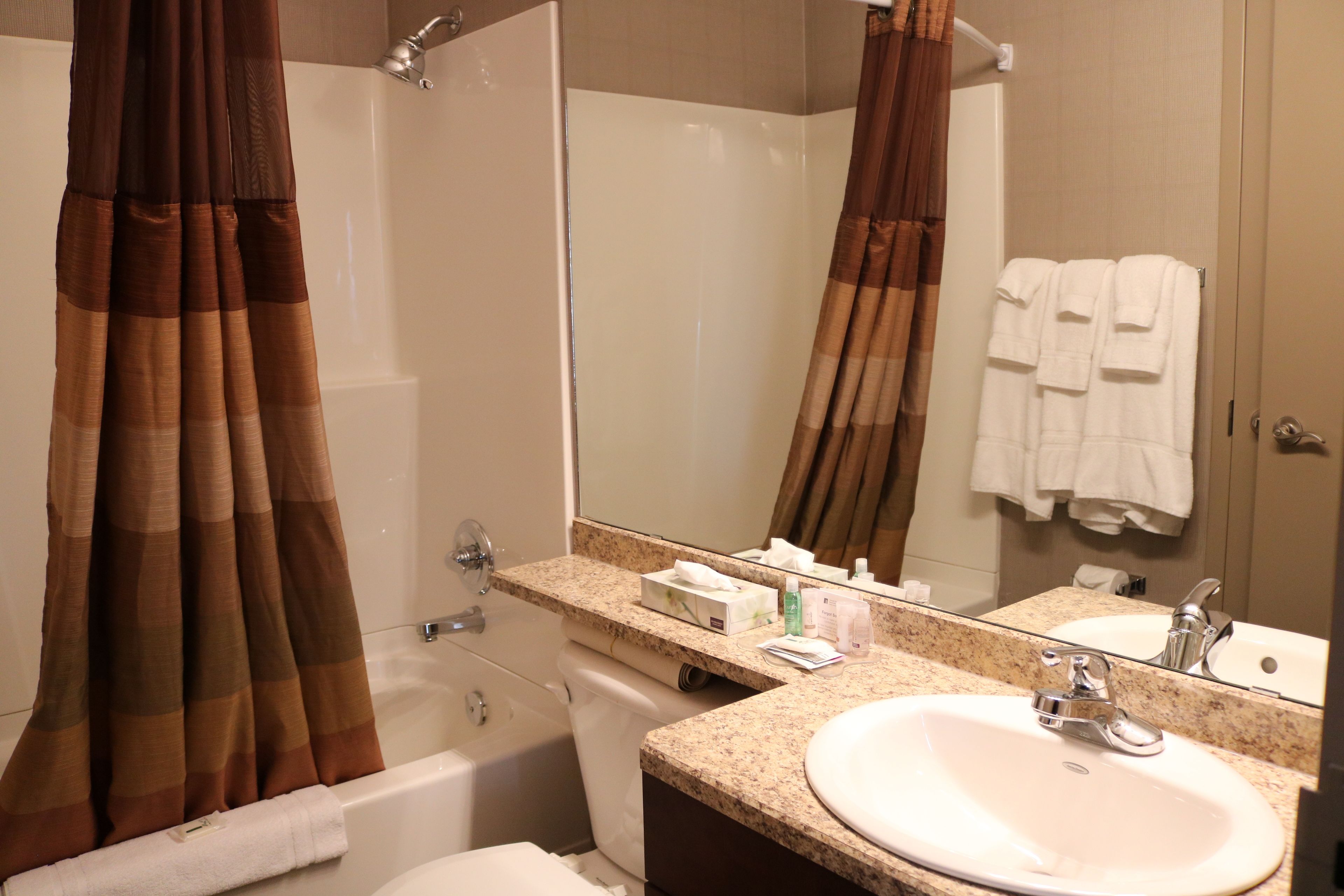 Un baño con bañera, lavabo, espejo y toallero.
