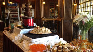 A buffet table with various food items, a large bowl of fruit, and a vase of flowers.
