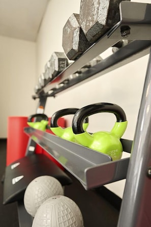 A gym equipment rack with kettlebells and dumbbells.