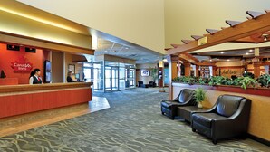A Canada Inn reception area with a red desk, black leather seating, and a wooden pergola.