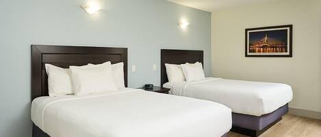 Two single beds with dark wooden headboards in a room with light blue walls and a framed picture on the wall.