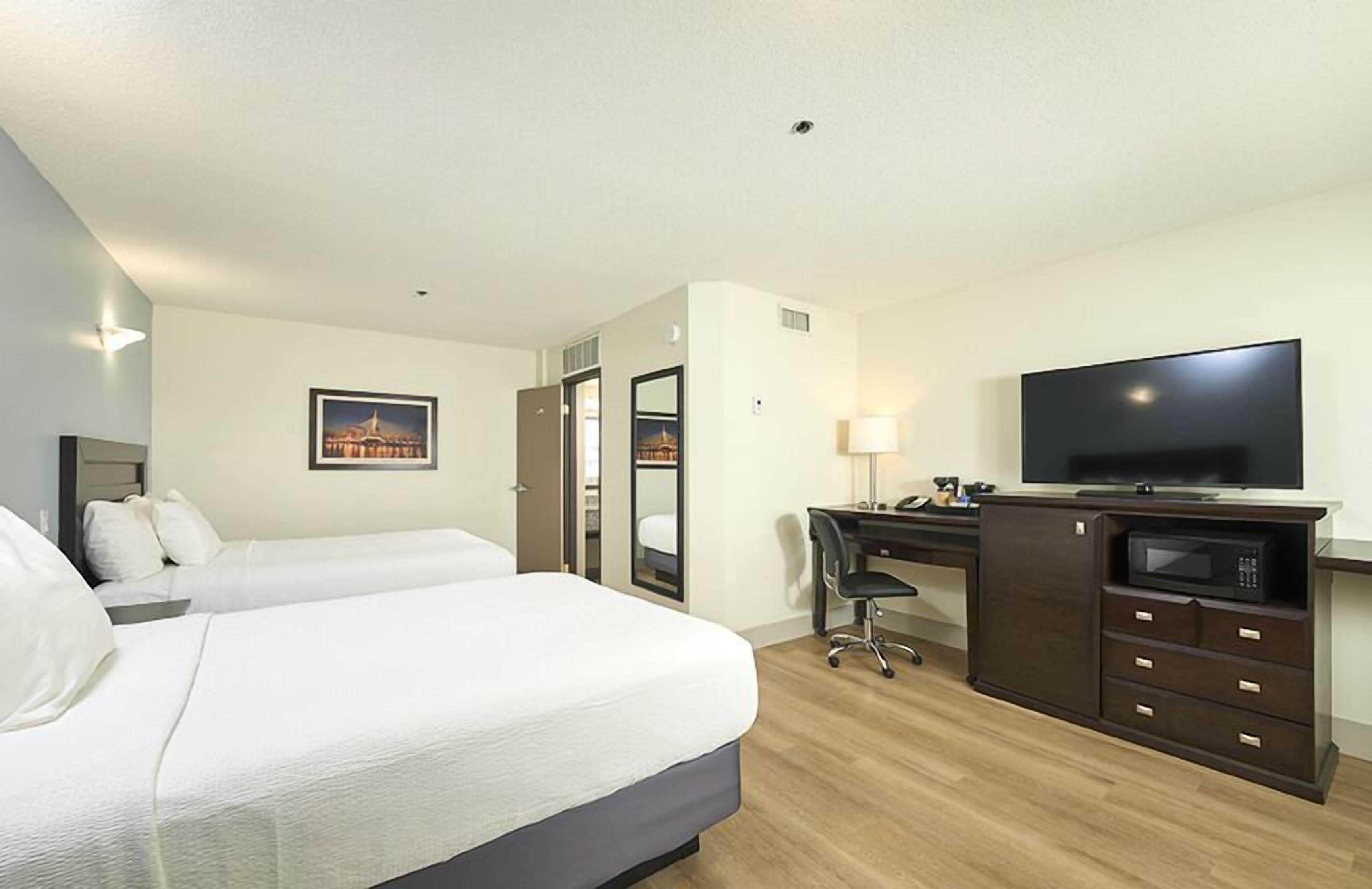 Een hotelkamer met twee bedden, een bureau, een televisie en een magnetron.