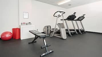 A gym with treadmills, a bench, and red exercise balls.