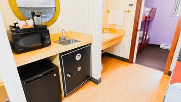 A compact kitchen with a microwave, sink, and small refrigerator.