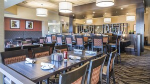 A hotel dining area with multiple tables and chairs, a reception desk, and a patterned carpet. - Quality Hotel & Conference Centre Fort McMurray (Fort McMurray)