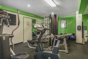 Un gimnasio con máquinas de cardio, equipo de levantamiento de pesas y pelotas de ejercicio.