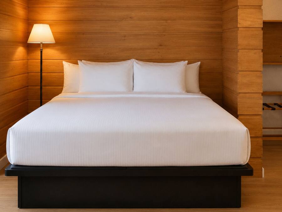 A bed with white linens, a black base, and a wooden headboard.