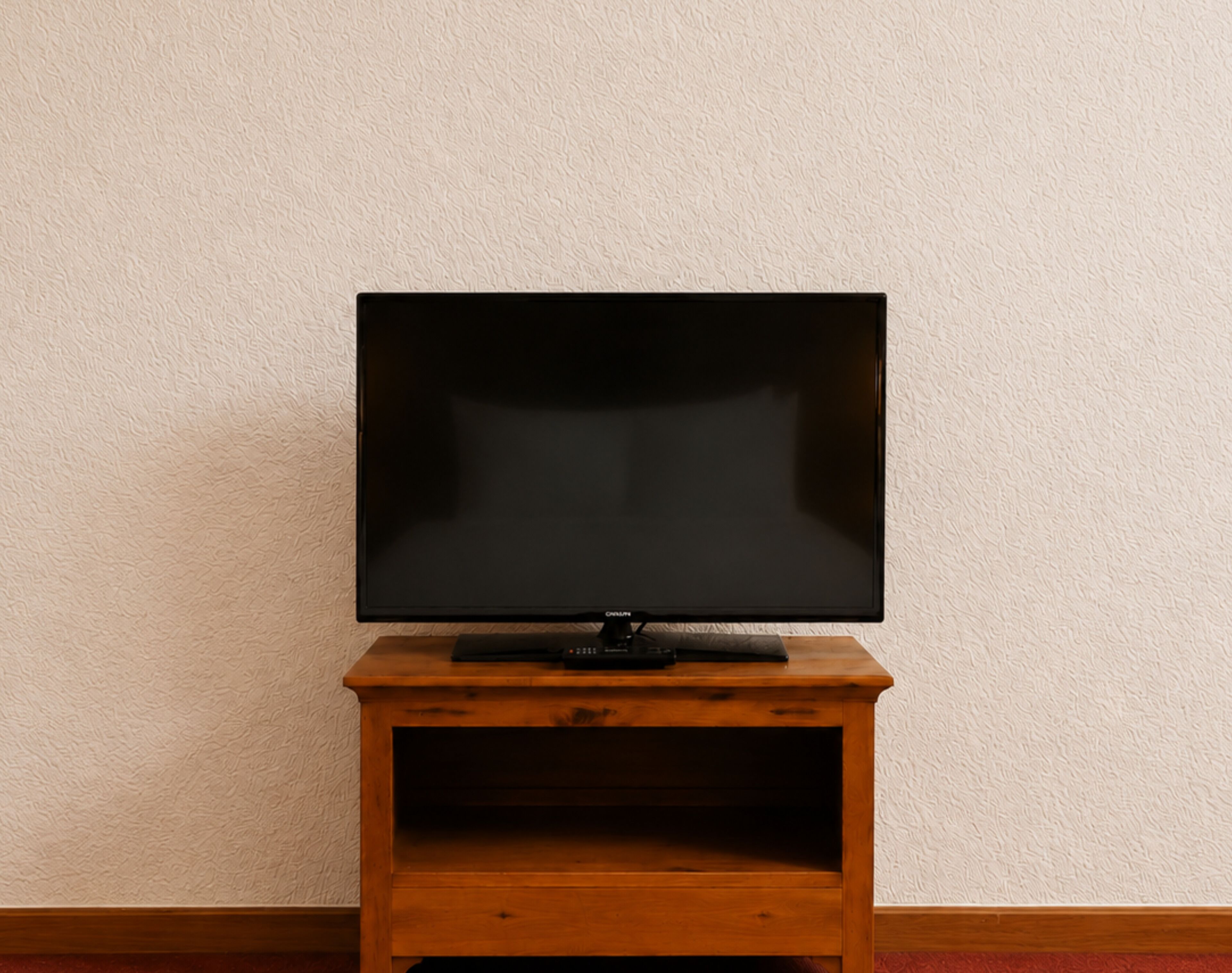 A television on a wooden stand against a textured wall.