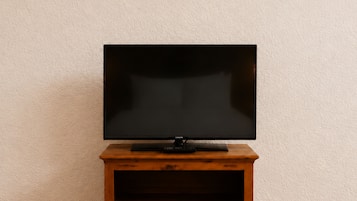 A television on a wooden stand against a textured wall.