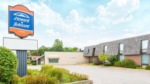 Un hôtel Howard Johnson avec une grande enseigne, un parking et un bâtiment à la façade en briques.