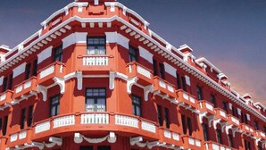 Un edificio de varios pisos con un diseño de esquina característico, que incluye balcones y ventanas grandes.