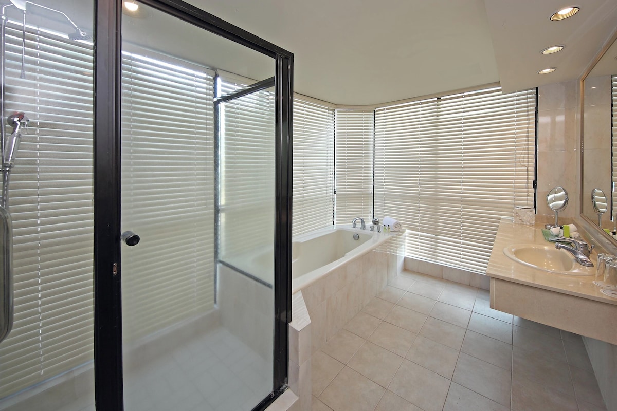 A modern bathroom with a glass-enclosed shower, a freestanding bathtub, and a vanity with a mirror and towel rack.