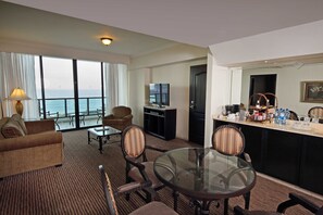 A hotel room with a balcony, a sofa, a dining table, chairs, a TV, a minibar, and a view of the sea. - InterContinental Miramar Panama by IHG (Panama City)