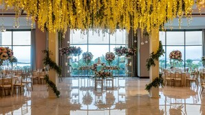 Un amplio salón con piso pulido, ventanas grandes y elegantes arreglos florales.
