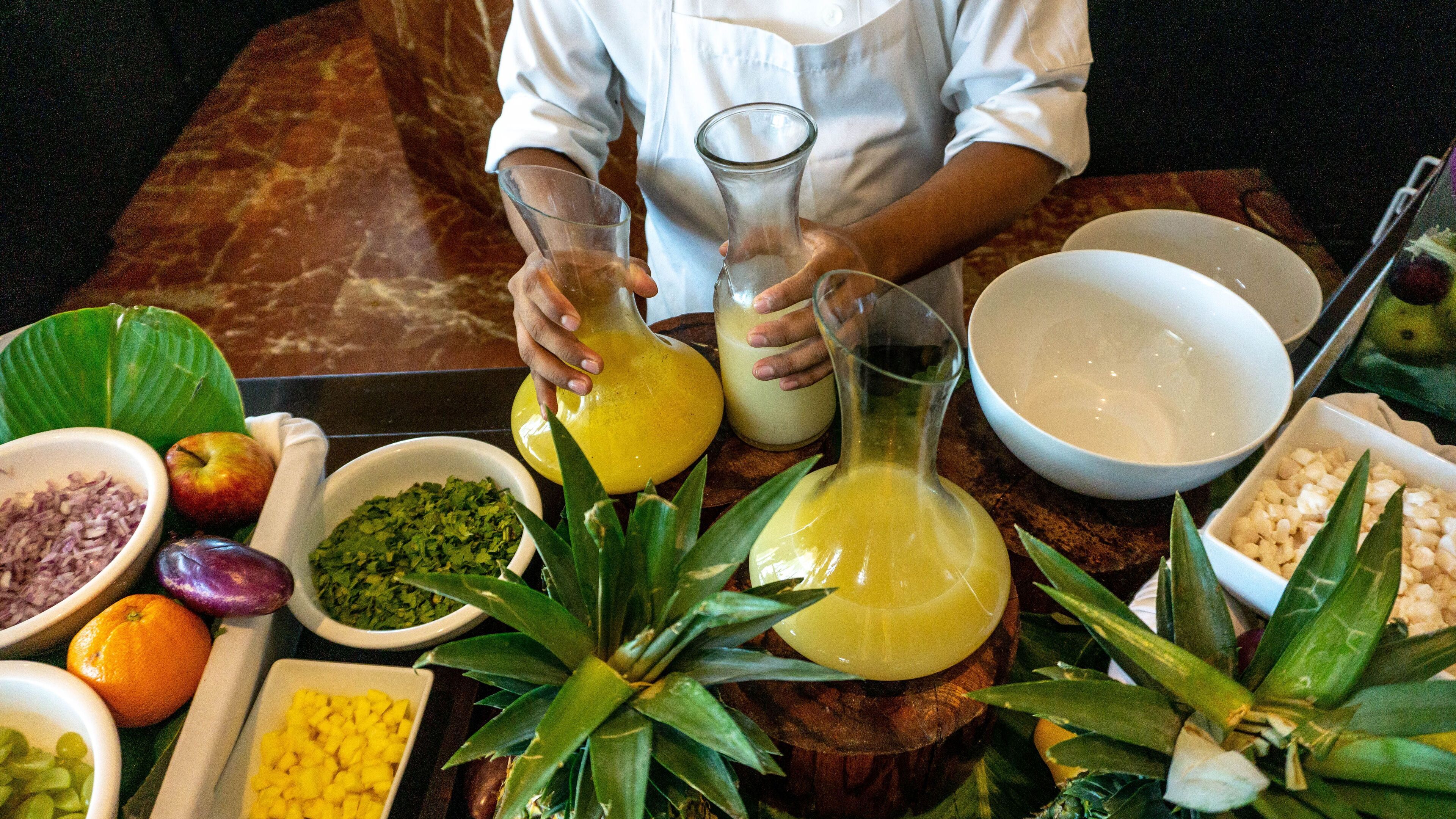 Un chef preparando un plato con diversos ingredientes y utensilios de cocina sobre una mesa de madera.