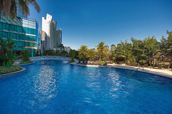 Una piscina al aire libre, sombrillas, tumbonas