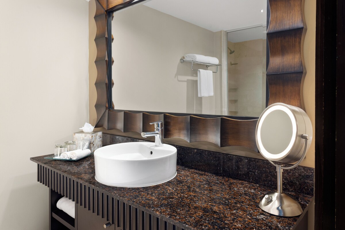 A bathroom with a white sink, a mirror, and a towel rack.