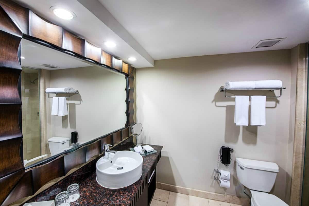 A modern bathroom with a large mirror, a sink, and a toilet.