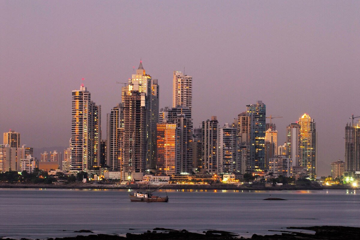A city skyline with high-rise buildings and a body of water in the foreground.